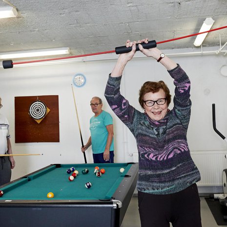 Malla Kuusisaari vahvistaa vatsa-lihaksiaan senioritalon kuntosalilla. Pekka Kuusisaari ja Veikko Muurinen ottavat  biljardimatsin.