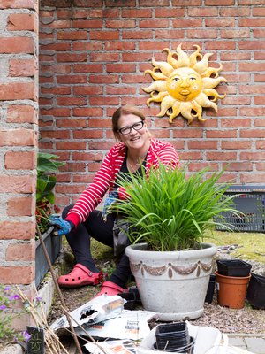 Muurin rajaama nurkka saa vihreyttä, kun Eija siirtää maassa talvehtineet tarhapäivänliljat, saniaiset ja kuunliljat kesäksi ruukkuihin.