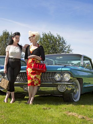 Toisiaan täydentävä kaksikko. Tummatukkaisen Netan sinivalkoinen Oldsmobile Holiday Sedan on vuodelta 1957. Vaalean Lotan auto on Cadillac Sedan Deville vuodelta 1961. Itse he eivät autojaan juuri fiksaile – miehet ovat sitä varten.