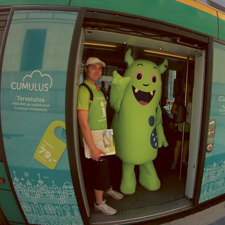 Helppi-hahmo auttaa turisteja Helsingissä.