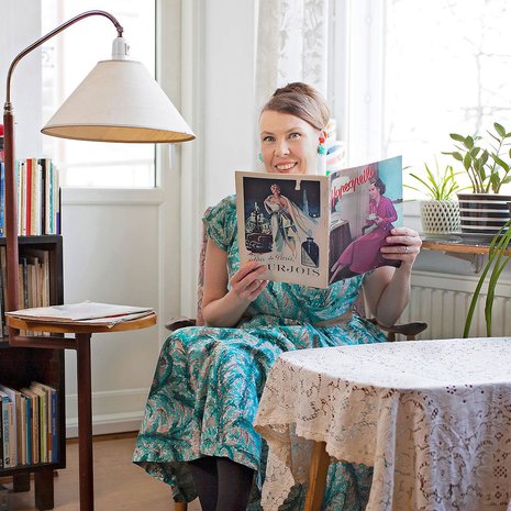 Elina Teerijoki 1950-luvun Stockmannin leningissä Hopeapeili-lehden kera. Valaisimellinen sivupöytä löytyi Raision Ekotila -kierrätys­keskuksesta.