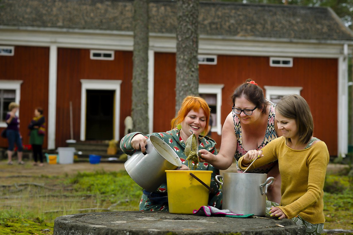 Noora Lappi, Sari Sheare ja Susanna Kuorikoski siivilöivät keitettyjä raparperinvarsia pois värjäysliemestä.