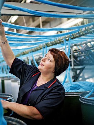 Kirsti Tuviala on viihtynyt talossa yli 20 vuotta. H&auml;n on joka paikan h&ouml;yl&auml;, mutta suosikki on kehruukone. T&ouml;it&auml; paiskitaan kahdessa vuorossa klo 6&ndash;14 ja 14&ndash;22. Tuotannossa on 80 ihmist&auml;.&ndash; Aikanani on tullut paljon uusia koneita ja langat ovat tulleet v&auml;rikk&auml;&auml;mmiksi, Kirsti kertoo.