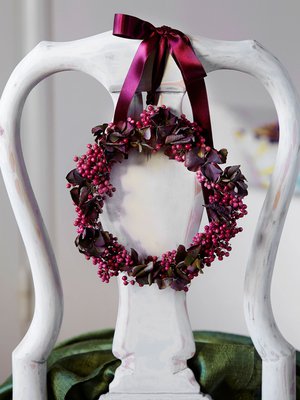 Ruokap&ouml;yd&auml;n tuoli ansaitsee juhla-asun. Silkkinauhalla selk&auml;nojaan solmittu seppele on taivuteltu pippurinmarjoista ja hortensian kukinnoista.