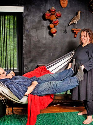 Arja luki lehdestä, että musta on sisustuksen trendiväri – ja vetäisi olohoneen mustaksi uunia myöten. Aarne ehti kummankin rakastamaan verkkokeinuun ensin. Nurkassa rehottaa papyrus.