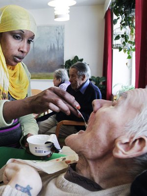 Lähihoitaja Nafra Jusuf työskentelee Kustaankartanon vanhustenkodissa. Tässä hän syöttää Pekka Flikmania.