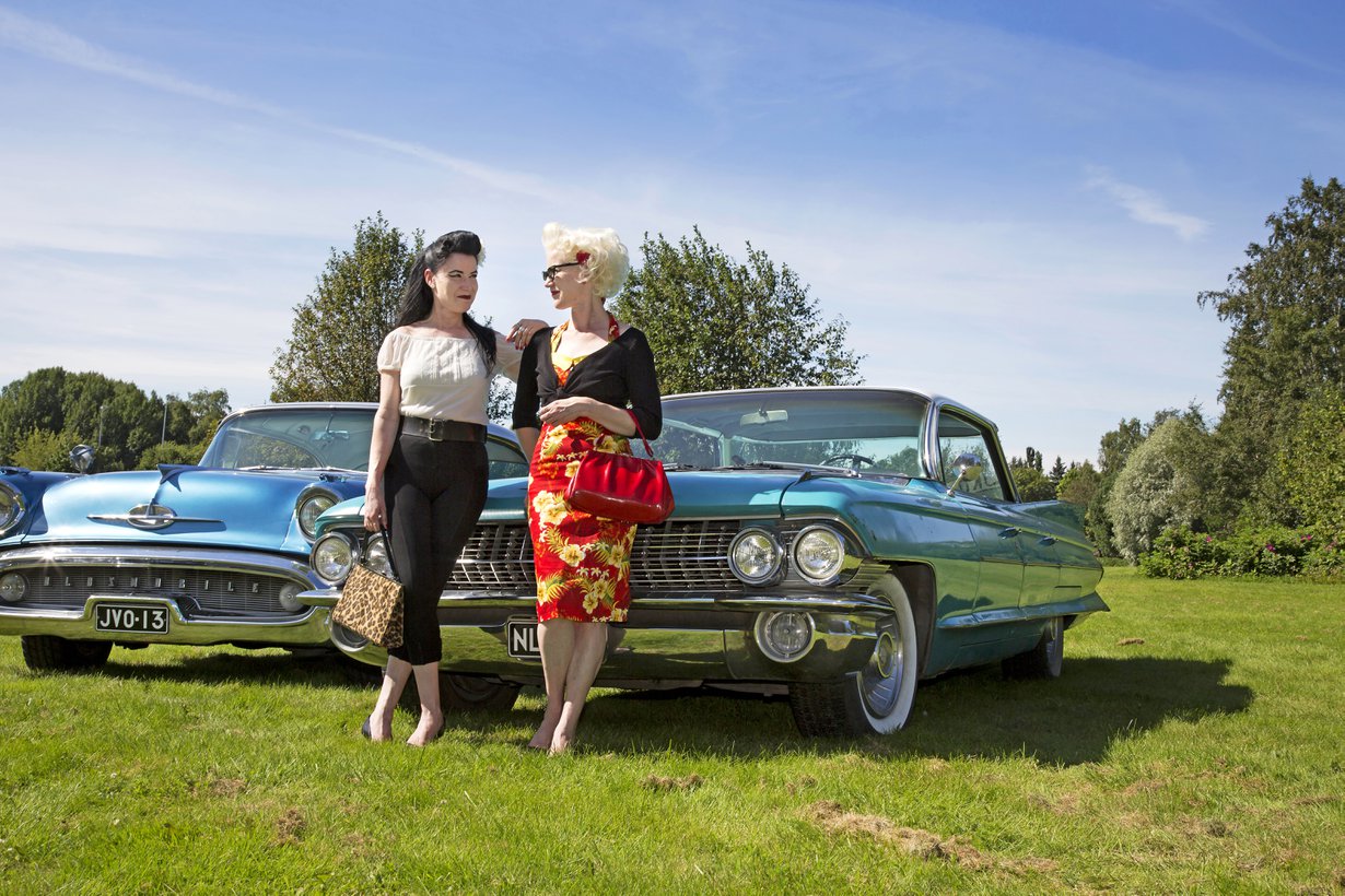 Toisiaan täydentävä kaksikko. Tummatukkaisen Netan sinivalkoinen Oldsmobile Holiday Sedan on vuodelta 1957. Vaalean Lotan auto on Cadillac Sedan Deville vuodelta 1961. Itse he eivät autojaan juuri fiksaile – miehet ovat sitä varten.