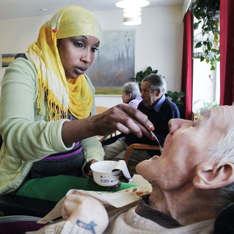 Lähihoitaja Nafra Jusuf työskentelee Kustaankartanon vanhustenkodissa. Tässä hän syöttää Pekka Flikmania.