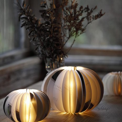 Lasipurkkiin liimattavat paperiympyrät muodostavat jämptin pallolyhdyn. Talvinen tunnelma syntyy, kun käytät lyhtyyn kalenterista lumisilla kuvilla somistetut marras–helmikuun sivut.