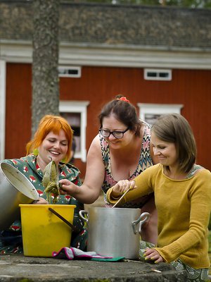 Noora Lappi, Sari Sheare ja Susanna Kuorikoski siivilöivät keitettyjä raparperinvarsia pois värjäysliemestä.