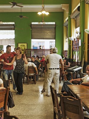 Kuubalaismies tanssittaa turistia levymusiikin tahdissa, kun bändi on tauolla vanhankaupungin Obispo-kadun La Lluvia de Orossa.